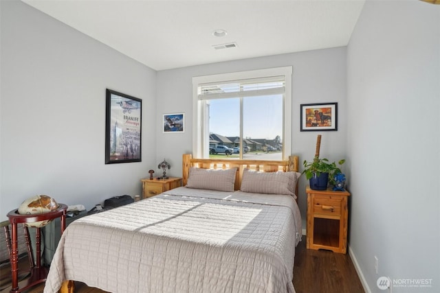 bedroom featuring baseboards, visible vents, and wood finished floors
