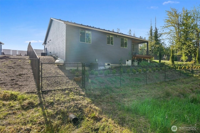 back of property with a fenced backyard, a gate, and a balcony