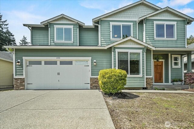 craftsman house with driveway, an attached garage, and stone siding
