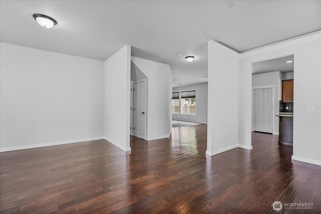 unfurnished living room with wood finished floors and baseboards