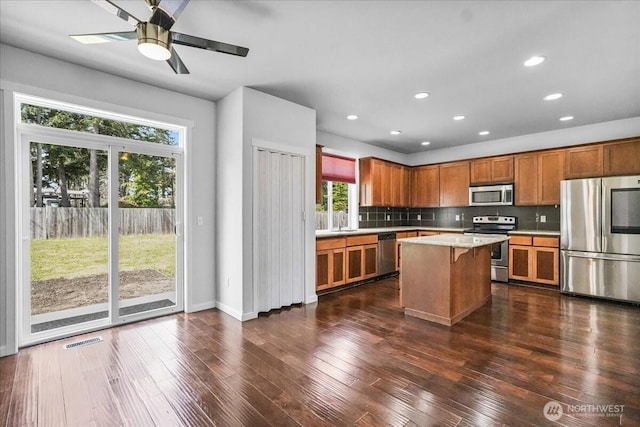 kitchen featuring stainless steel appliances, a sink, brown cabinetry, light countertops, and decorative backsplash
