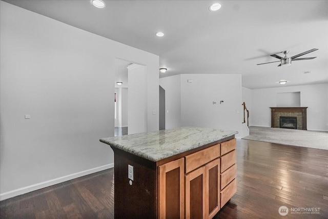 kitchen featuring ceiling fan, dark wood-style floors, a tiled fireplace, baseboards, and recessed lighting