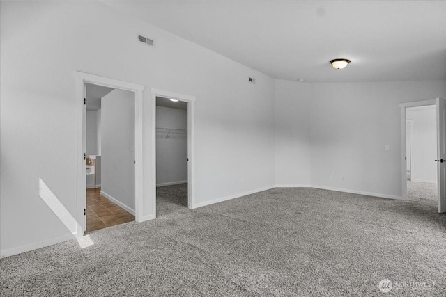 unfurnished bedroom featuring carpet floors, a walk in closet, baseboards, and a closet