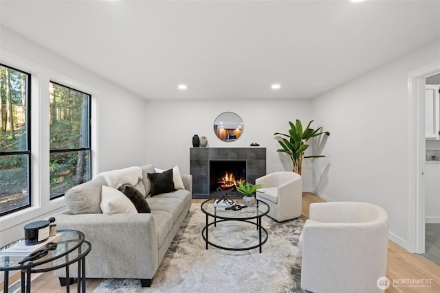 living area with recessed lighting, baseboards, light wood-type flooring, and a tile fireplace