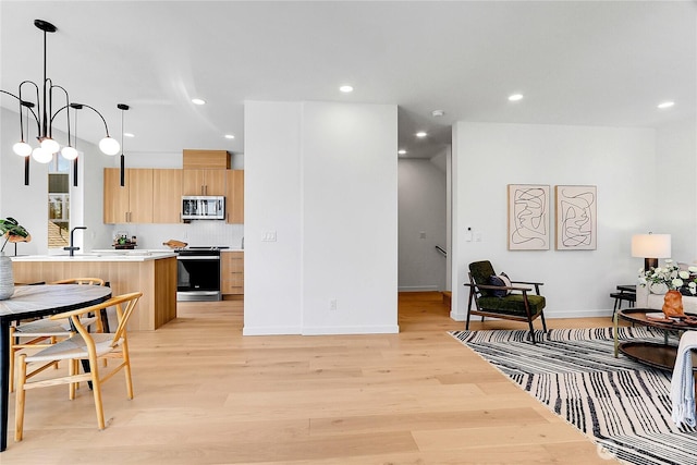 627A W Emerson St, Seattle, WA 98119 - kitchen with light brown cabinets, light wood-type flooring, light countertops, stainless steel microwave, and range with electric cooktop