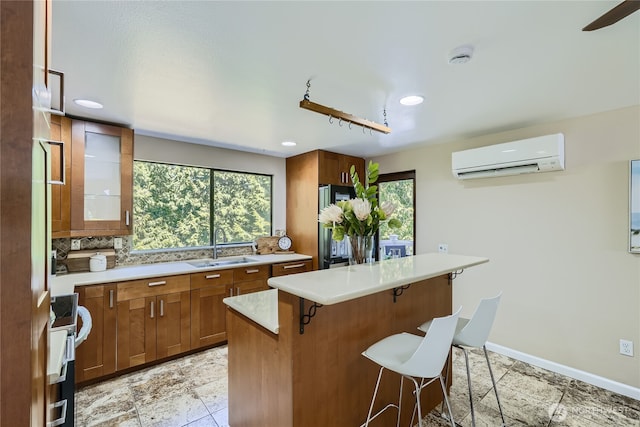 22606 NE 14th Dr, Sammamish, WA 98074 - kitchen featuring brown cabinets, a sink, a wall mounted air conditioner, light countertops, and a kitchen breakfast bar