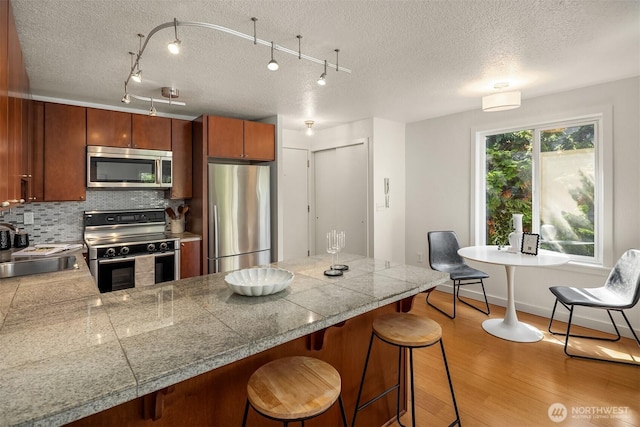 1751 NW 58th St Unit 4, Seattle, WA 98107 - kitchen with tile counters, appliances with stainless steel finishes, a sink, and a peninsula