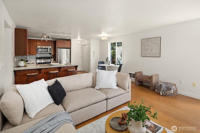 1751 NW 58th St Unit 4, Seattle, WA 98107 - living room featuring rail lighting, baseboards, and light wood-type flooring
