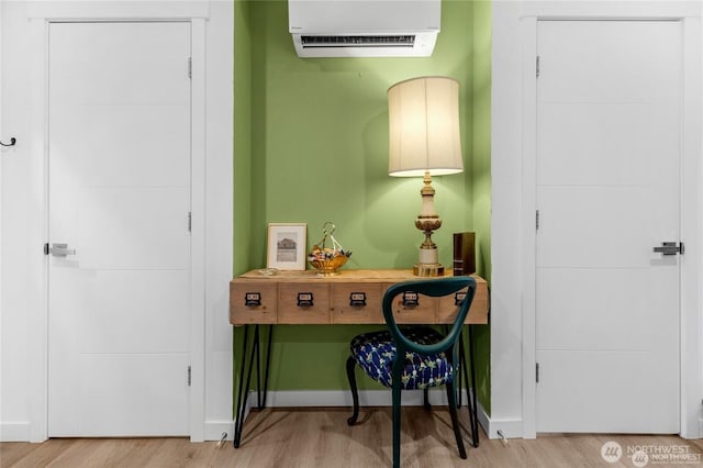 interior space featuring an AC wall unit, baseboards, and wood finished floors