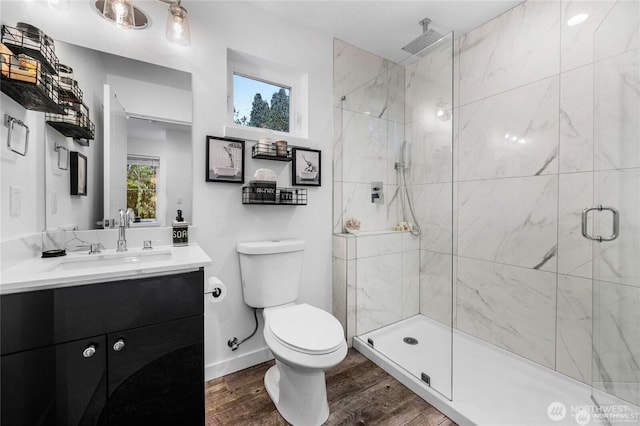 full bath with a shower stall, wood finished floors, vanity, baseboards, and toilet