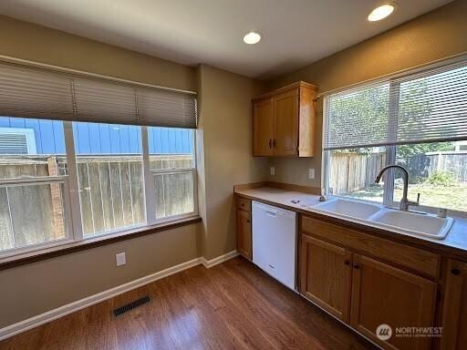 kitchen with visible vents, dark wood finished floors, dishwasher, a sink, and baseboards