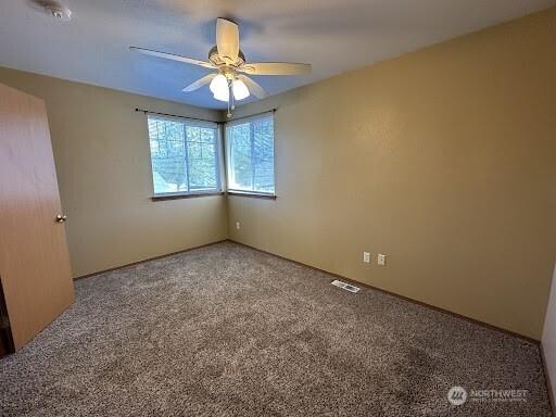 unfurnished room with carpet floors, ceiling fan, and visible vents