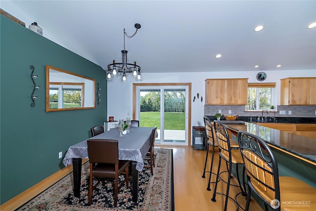 dining area with light wood-type flooring, recessed lighting, and an inviting chandelier