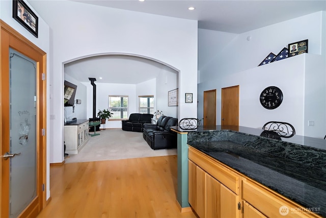 kitchen featuring dark stone counters, arched walkways, recessed lighting, and light wood-style flooring
