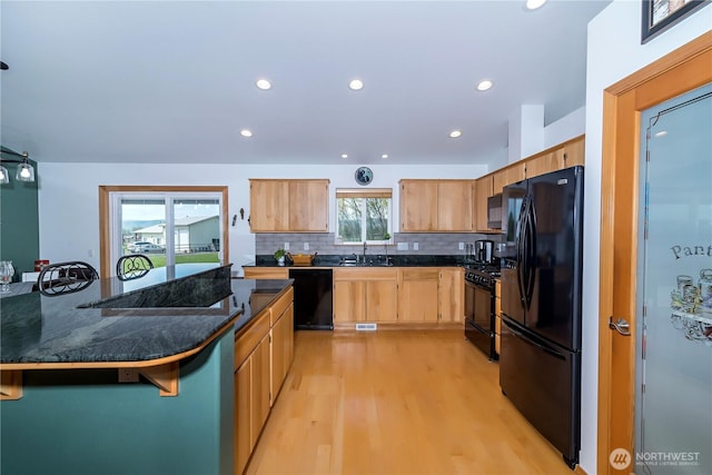 kitchen with decorative backsplash, light wood-type flooring, a sink, black appliances, and recessed lighting