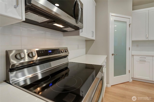 18214 37th Ave E, Tacoma, WA 98446 - kitchen with backsplash, white cabinets, appliances with stainless steel finishes, and light wood finished floors