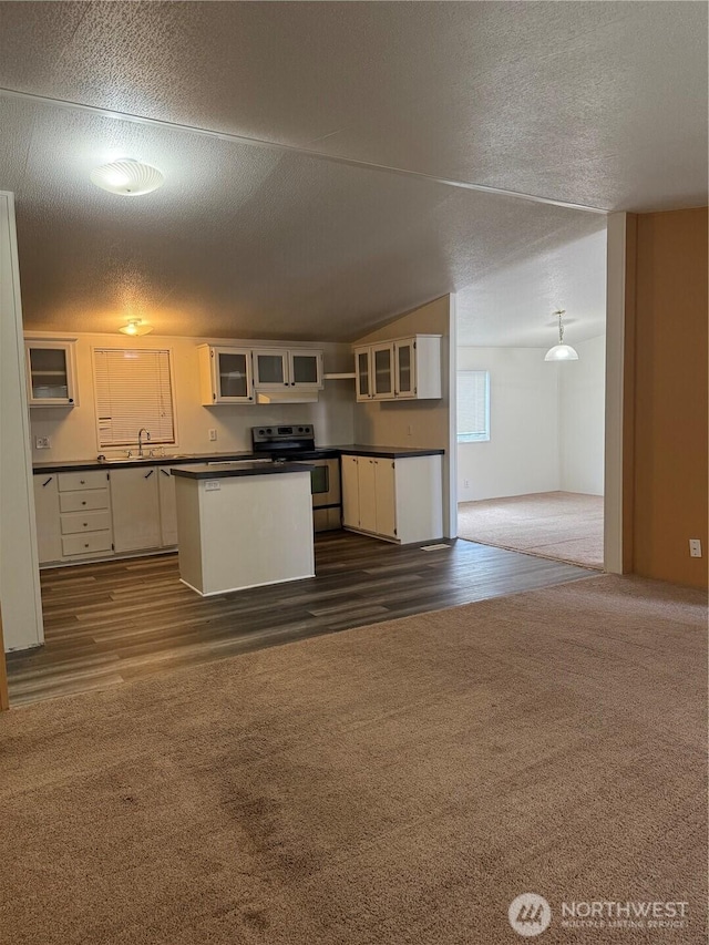 kitchen with stainless steel electric range, dark countertops, a sink, and dark carpet