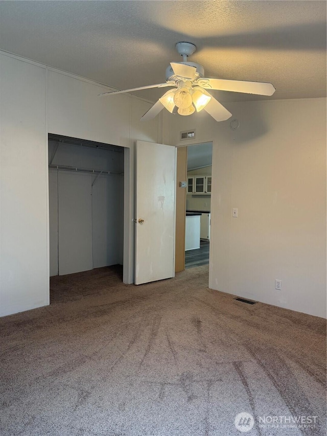 unfurnished bedroom with visible vents, carpet, ceiling fan, and a closet