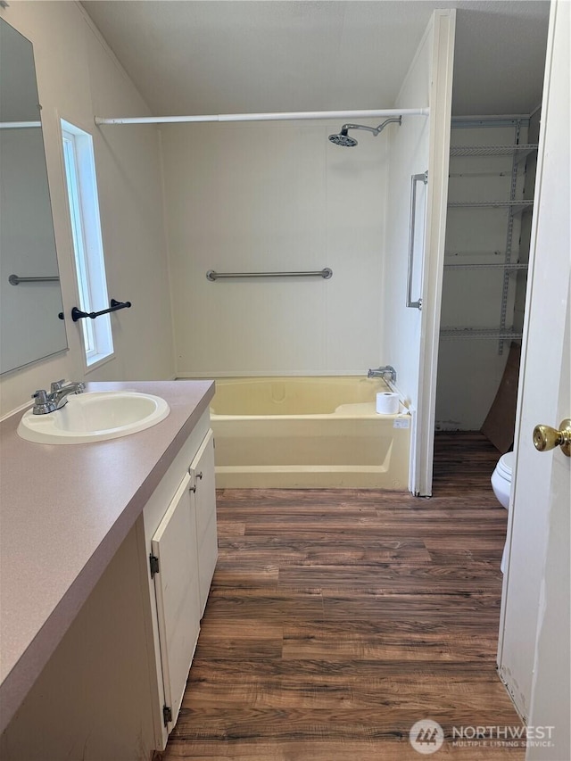 bathroom with vanity, wood finished floors, toilet, and bathing tub / shower combination