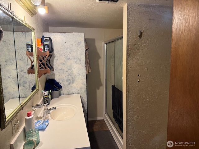 bathroom with vanity, a textured ceiling, and a stall shower