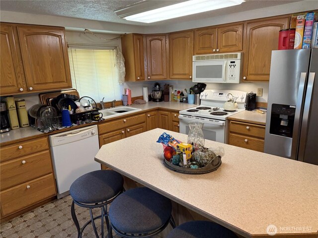 kitchen featuring white appliances, a kitchen breakfast bar, a sink, and light countertops