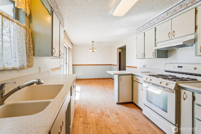 1015 14th St NW, Puyallup, WA 98371 - kitchen featuring white range with gas stovetop, light countertops, under cabinet range hood, a sink, and light wood finished floors