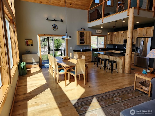 dining area featuring wooden ceiling, a wealth of natural light, wood finished floors, and a towering ceiling