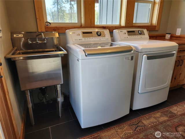 laundry area featuring dark tile patterned floors, laundry area, washing machine and dryer, and a sink