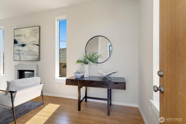 interior space featuring a glass covered fireplace, baseboards, and wood finished floors