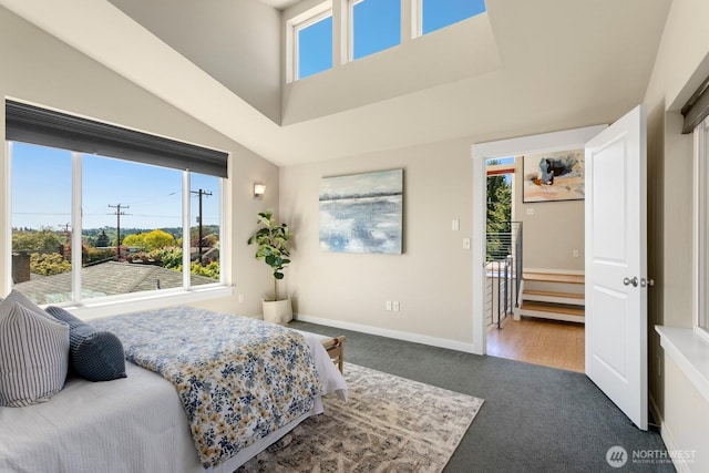 bedroom with carpet floors, multiple windows, baseboards, and a high ceiling