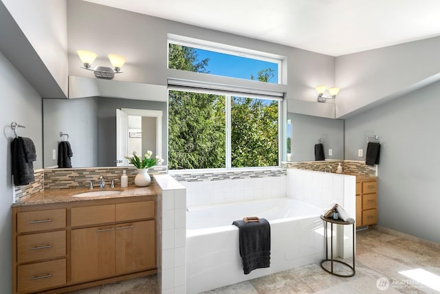 full bath featuring vanity, decorative backsplash, and a garden tub