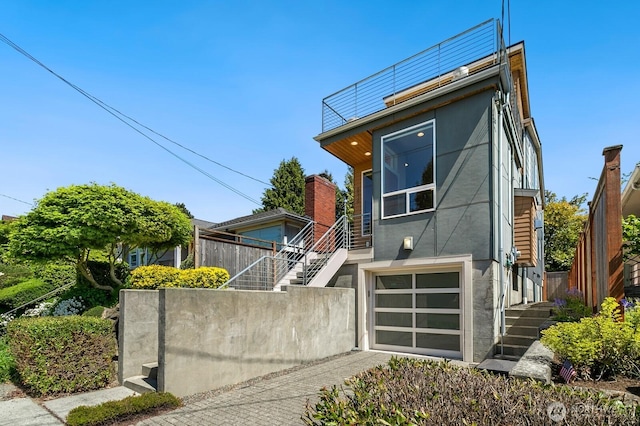 contemporary home featuring a garage, stucco siding, and stairway