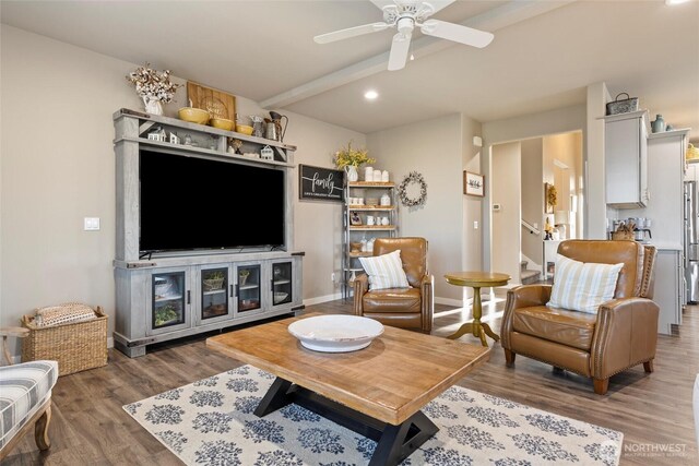 living room with stairway, beamed ceiling, a ceiling fan, and wood finished floors