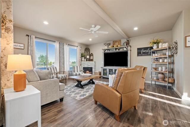 living area with a ceiling fan, beamed ceiling, dark wood-style floors, and a fireplace