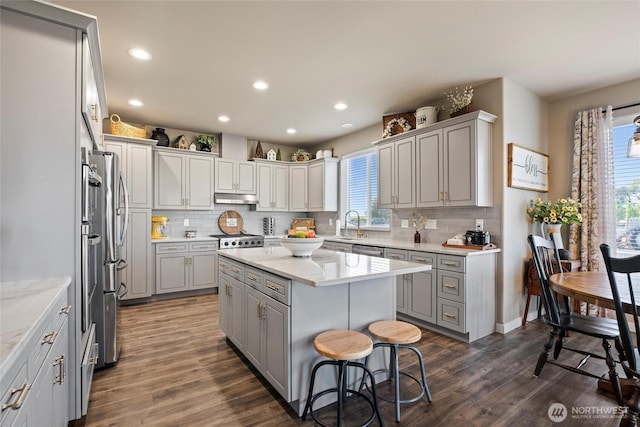 kitchen with a center island, backsplash, dark wood-style floors, and gray cabinetry