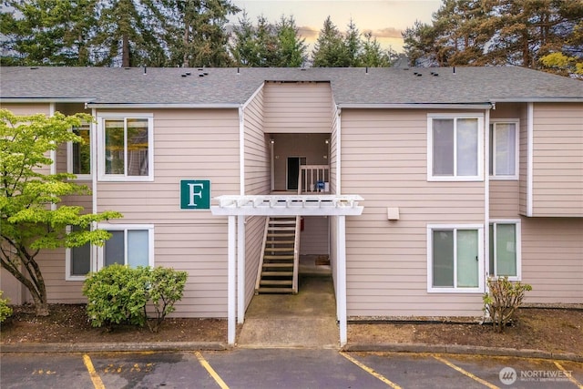 back of house featuring uncovered parking and stairs