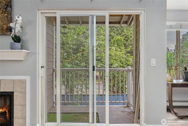 doorway to outside featuring a baseboard heating unit and a tile fireplace