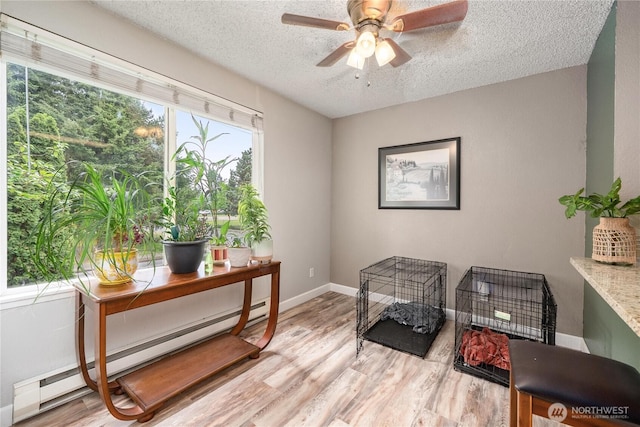 office area featuring a baseboard radiator, wood finished floors, a textured ceiling, ceiling fan, and baseboards
