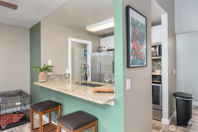 bathroom with a sink, wood finished floors, a textured ceiling, backsplash, and baseboards