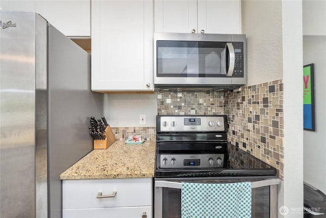 kitchen featuring appliances with stainless steel finishes, tasteful backsplash, white cabinetry, and light stone countertops