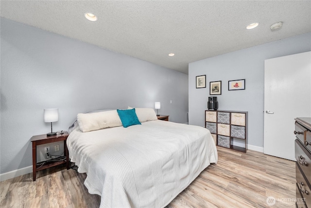 bedroom featuring light wood-type flooring, baseboards, a textured ceiling, and recessed lighting