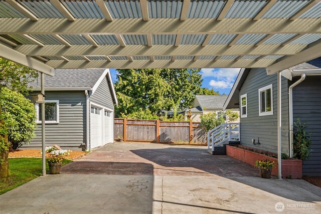 view of patio featuring fence, concrete driveway, and an attached garage