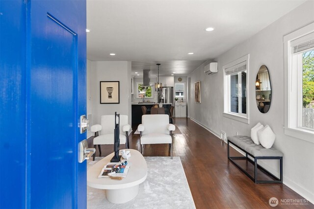 living room with a wall mounted air conditioner, dark wood-type flooring, recessed lighting, and baseboards