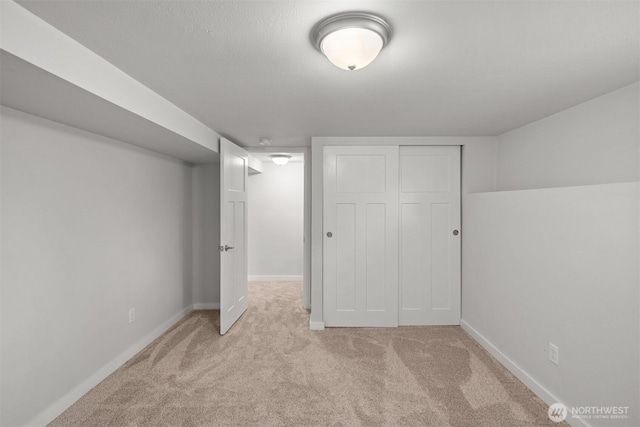 finished below grade area featuring light carpet and baseboards