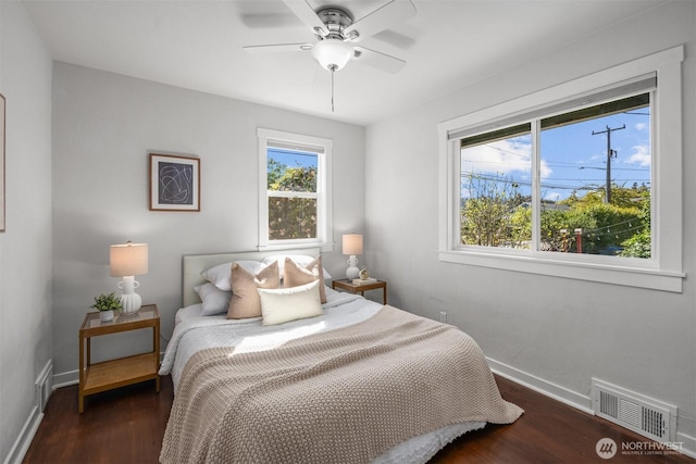 bedroom with multiple windows, wood finished floors, baseboards, and a ceiling fan