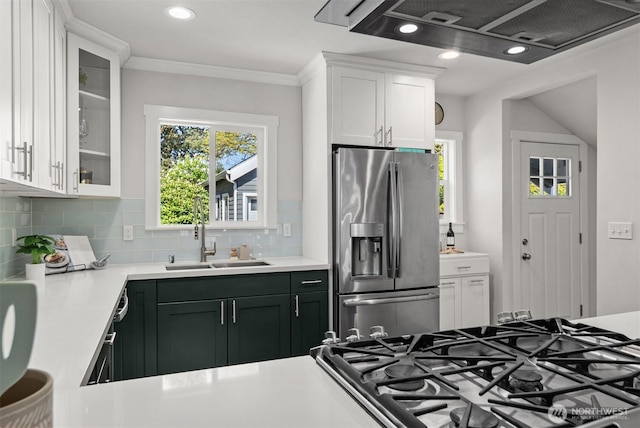 kitchen with stainless steel refrigerator with ice dispenser, a sink, range hood, white cabinetry, and tasteful backsplash