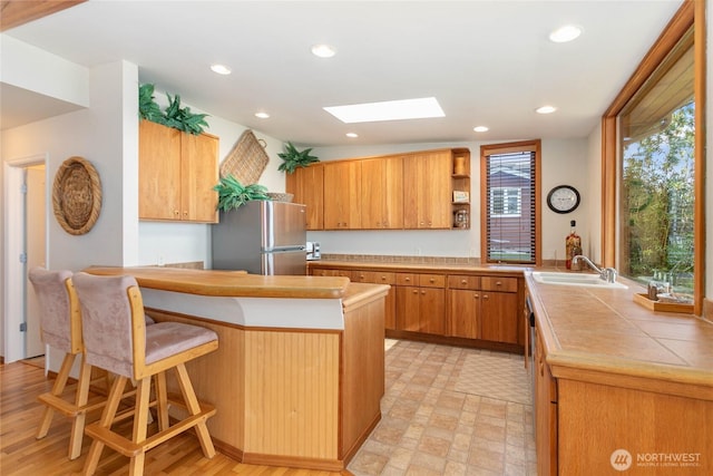 3003 Haxton Way, Bellingham, WA 98226 - kitchen featuring freestanding refrigerator, a sink, a skylight, a peninsula, and a breakfast bar area