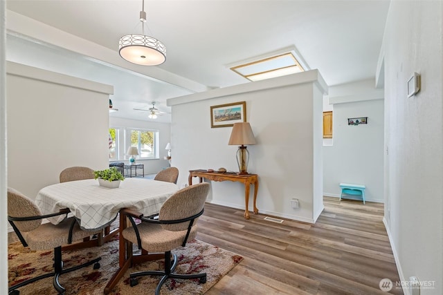 dining space with a ceiling fan, baseboards, visible vents, and wood finished floors