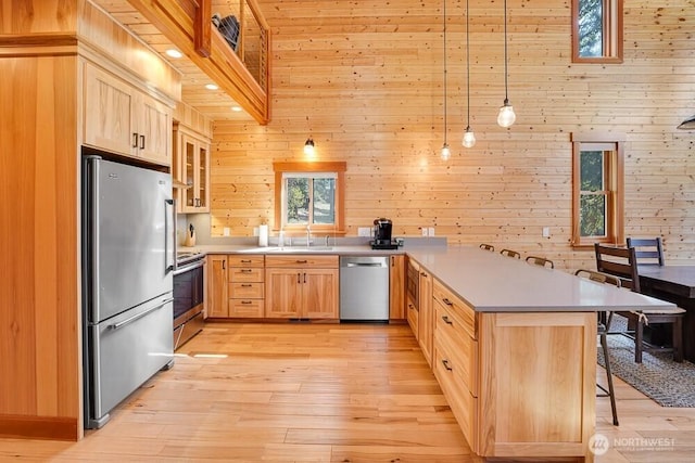 kitchen with a sink, appliances with stainless steel finishes, light brown cabinets, and a peninsula