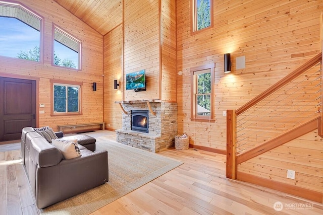 living area featuring wood walls, wood finished floors, a stone fireplace, high vaulted ceiling, and wooden ceiling